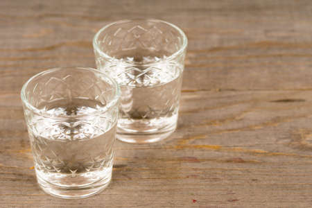 vodka in shot glasses on rustic wooden tableの写真素材