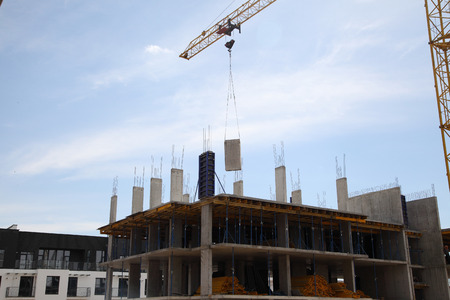 A modern new building. Working crane on the construction of the house. Construction site with cranes...