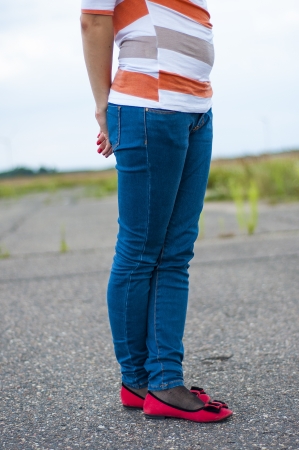 Female legs with blue jeans anb red shoes on the streetの写真素材