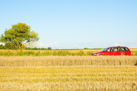 Red car parked near the wheat fieldの写真素材