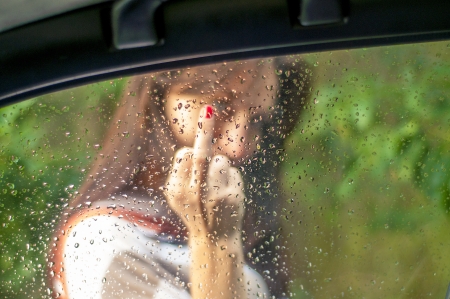An image of girl showing her middle finger  Focus on the windowの写真素材