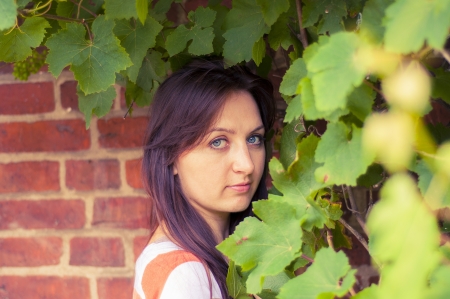 An image of girl hiding in the grapevines against brick wallの写真素材