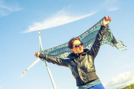 An image of girl holding canvas-cape and windturbine in backgroundの写真素材