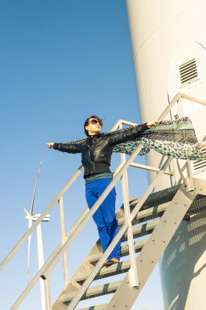 An image of girl holding canvas-cape and windturbine in backgroundの写真素材