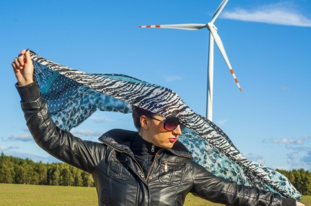 An image of girl holding canvas-cape and windturbine in backgroundの写真素材