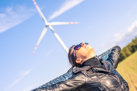 An image of girl holding canvas-cape and windturbine in backgroundの写真素材