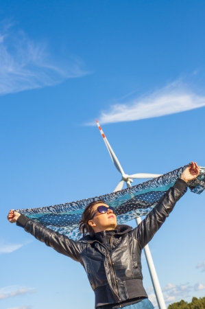 An image of girl holding canvas-cape and windturbine in backgroundの写真素材