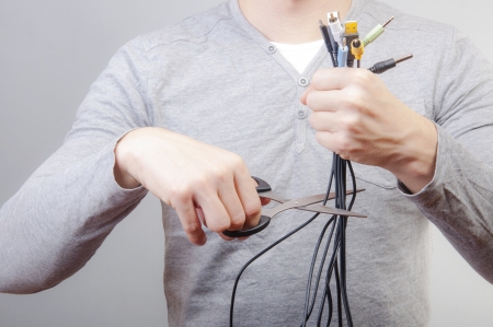 An image of man holding many cables with plug and scissors in other handの写真素材