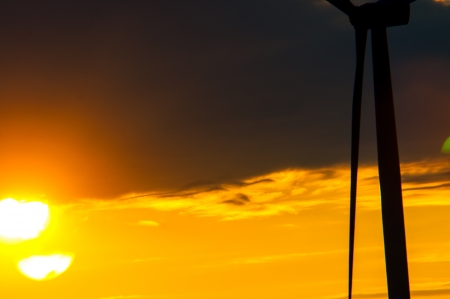 An image of wind turbines at sunset