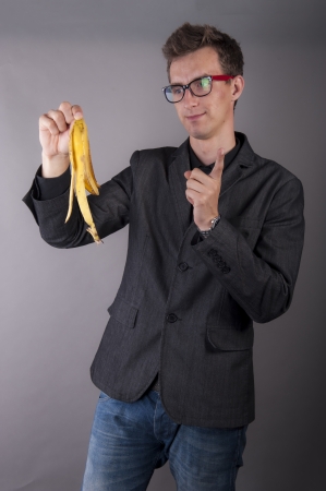 An image of young businessman holds a banana peelの写真素材