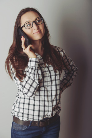 Happy brunette girl talking via smartphone at homeの写真素材