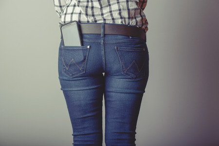 Woman takes out smartphone of her rear pocket of jeans