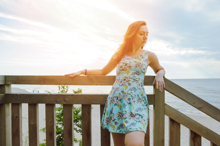 Brunette girl sitting on the wooden stairs in park and smilingの写真素材