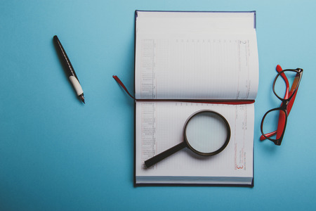 Business planning with copy space and office supplies. Magnifying glasses and red glasses on blue backgroundの写真素材