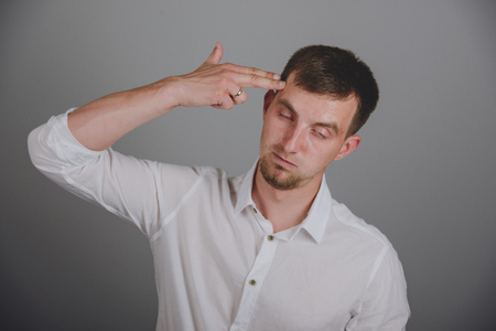 Portrait of young man pointing finger gun gesture to headの写真素材
