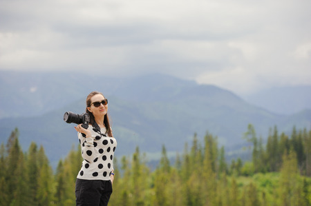 Woman photographer takes pictures in mountain in the summer