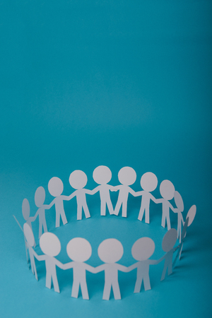 abstract paper people holding for hands on blue backgroundの写真素材