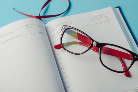 Business planning with copy space and office supplies. Red glasses on blue backgroundの写真素材