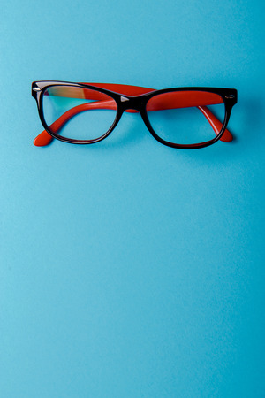 pair of red plastic-rimmed eyeglasses on a blue backgroundの写真素材