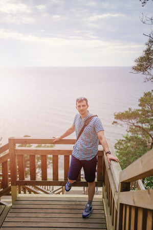 young man sitting on the wooden stairs in park and smilingの写真素材