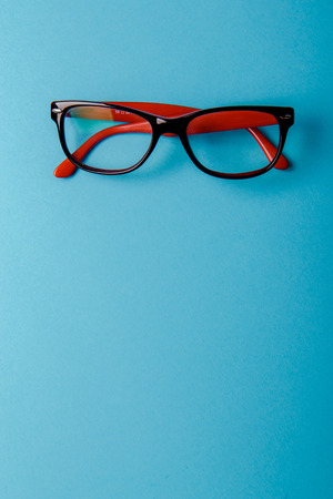 pair of red plastic-rimmed eyeglasses on a blue backgroundの写真素材