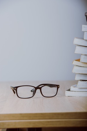 book and eyeglasses on wood background deskの写真素材