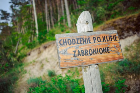 wooden warning signboard on beach at baltic sea