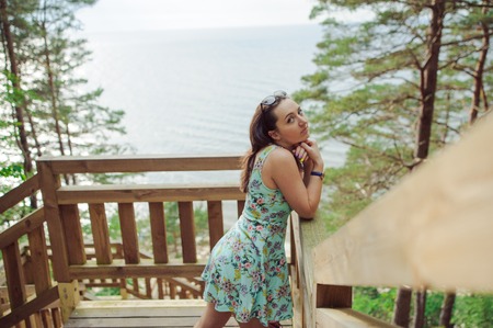 Brunette girl sitting on the wooden stairs in park and smilingの写真素材