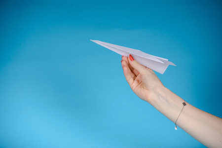 Paper plane in female hand on a blue backgroundの写真素材