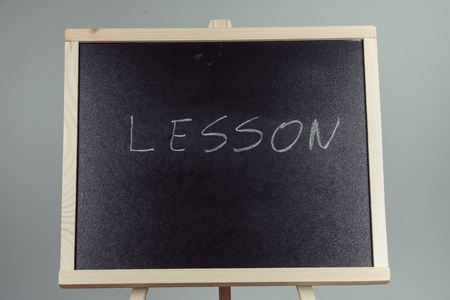 Lesson written in white chalk on a black chalkboard . gray backgroundの写真素材