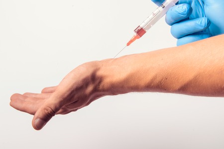 Hand in glove with syringe on white background. Injections.の写真素材