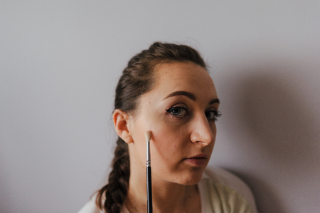 brunette girl applying make up at homeの写真素材