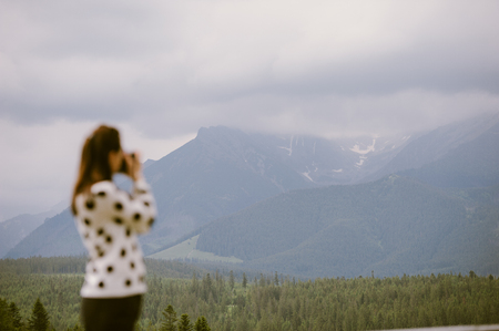 Woman photographer takes pictures in mountain in the summerの写真素材
