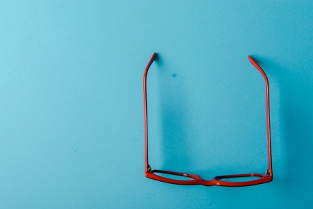 pair of red plastic-rimmed eyeglasses on a blue backgroundの写真素材