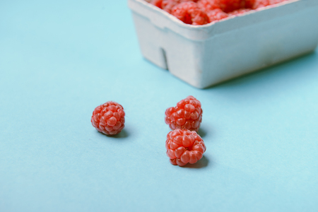 box of fresh raspberries on a blue backgroundの写真素材