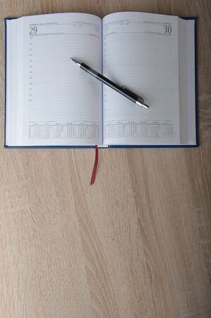 Notebook with pen on the wooden deskの写真素材