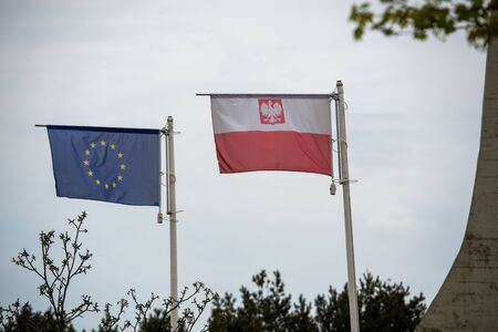 Polish national flags on a green major building in a slight breezeの写真素材