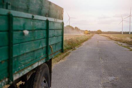 Green trailer and yellow harvester in the background. Harvest timeの写真素材