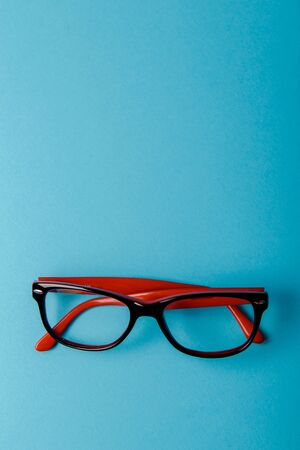 pair of red plastic-rimmed eyeglasses on a blue backgroundの写真素材