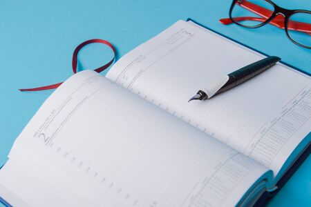 notebook on blue background. open diary and pen to recordの写真素材