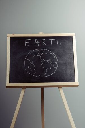 earth written on blackboard with earth symbol, background, high resolution, gray backgroundの写真素材