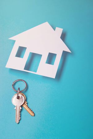 Silver key with house figure on blue background. Top view.の写真素材