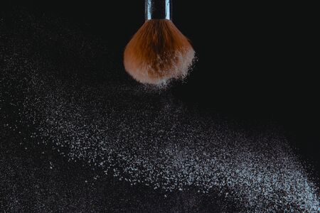 A photograph of Isolated make-up powder with brush on black backgroundの写真素材