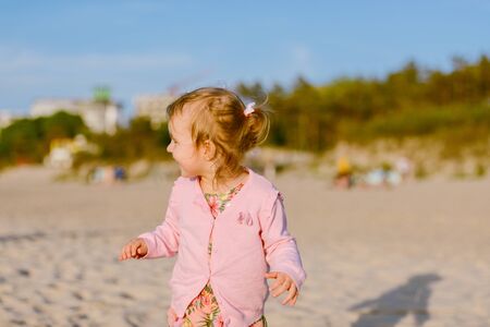 Adorable toddler girl on a sunny sand beach. Childhood