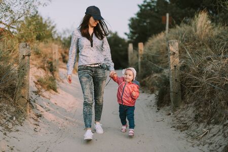 Mother and little daughter walking on the beach.の写真素材