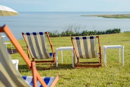 Empty beach chair on meadow on summer time. Sunlight and sea in the background. Coast lineの写真素材