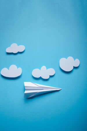 Paper plane in female hand on a blue background with cloudsの写真素材