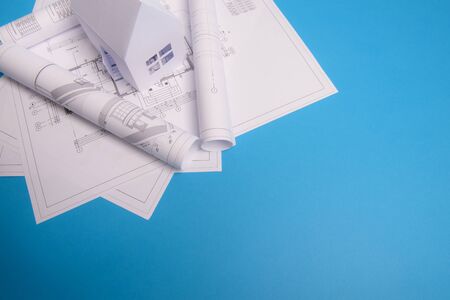White family paper house, house projects plan and blueprints in the background. Minimalistic and simple concept, style. Horizontal orientation. View from above.の写真素材