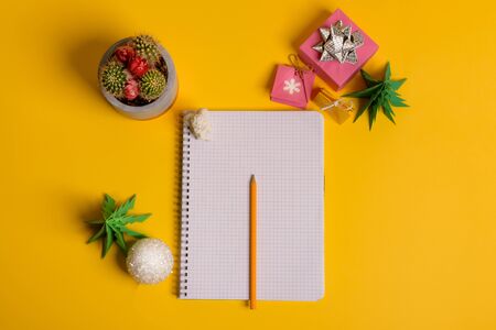 gift box and green origami trees with notepad on yellow desk, tableの写真素材