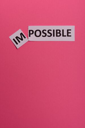 Impossible text cut out. Possible concept. Success. Pink background. Copy space. Vertical orientation. View from above. Minimal simple styleの写真素材